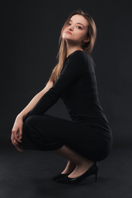Séance studio sur fond sombre d'une jeune femme en robe noire